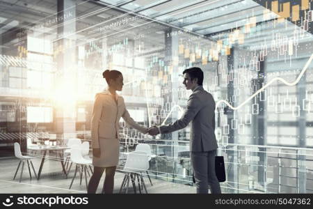 Business partnership handshake mixed media. Full length of businessmen shaking hands in office building