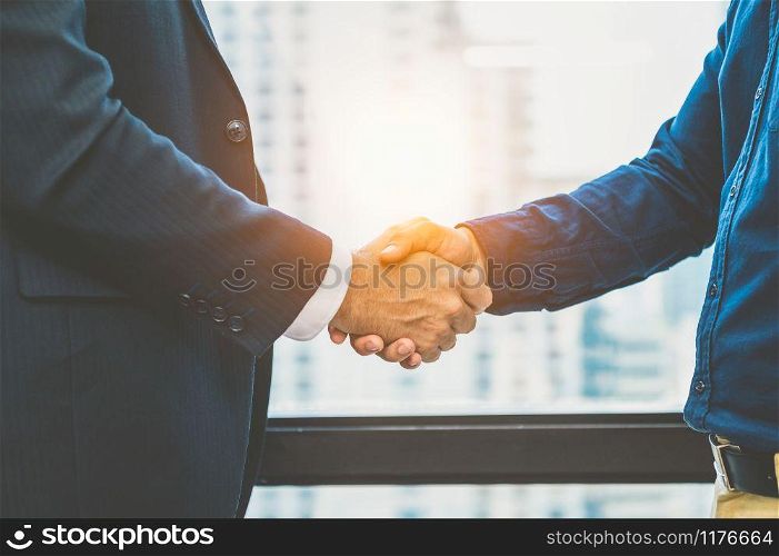 Business partnership meeting handshaking concept. Businessmen doing handshake. Successful business people contract handshaking after finished good dealing with skyscraper window building background.
