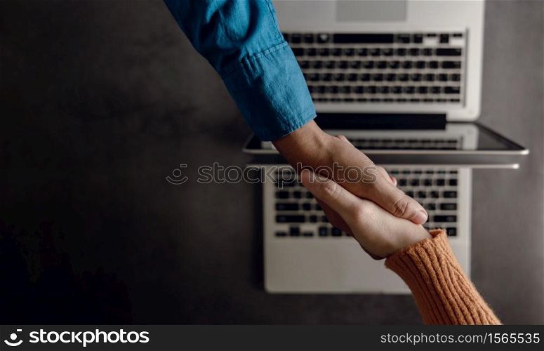 Business Partnership or Teamwork making Handshake. Successful Deal after Meeting. Top View. Blurred Working Desk with Laptop as background