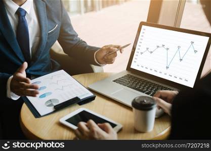 Business partnership pointing to the graph of the company financial statements report and profits earned during in the computer screen.