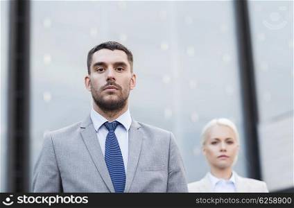 business, partnership, success and people concept - businessman and businesswoman standing over office building