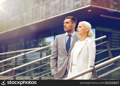 business, partnership, success and people concept - serious businessman and businesswoman standing over office building