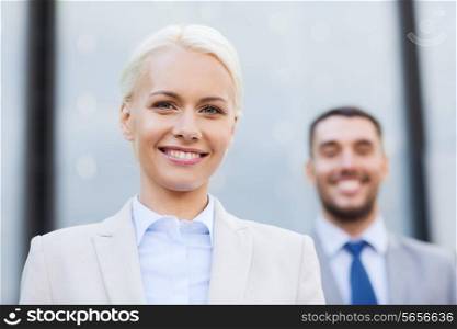 business, partnership, success and people concept - smiling businessman and businesswoman standing over office building