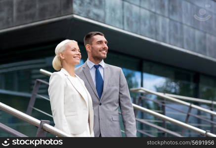 business, partnership, success and people concept - smiling businessman and businesswoman standing over office building