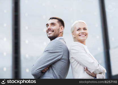 business, partnership, success and people concept - smiling businessman and businesswoman standing over office building