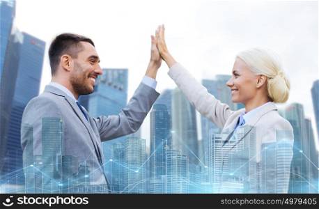 business, partnership, success, gesture and people concept - smiling businessman and businesswoman making high five over city and office buildings with charts background. businessman and businesswoman making high five
