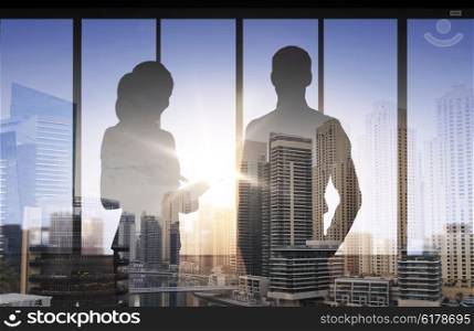 business, partnership, teamwork and people concept - silhouettes of partners over double exposure office and city background