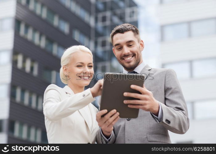 business, partnership, technology and people concept - smiling businessman and businesswoman with tablet pc computer over office building