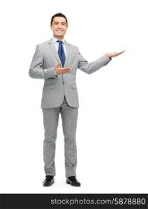 business, people, advertisement and office concept - happy smiling businessman in suit showing something imaginary
