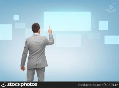 business, people, advertisement and technology concept - businessman pointing finger or touching blank virtual screen over blue background from back