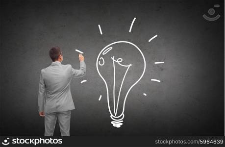business, people, advertisement , information and office concept - businessman drawing lighting bulb from back over dark gray concrete wall background