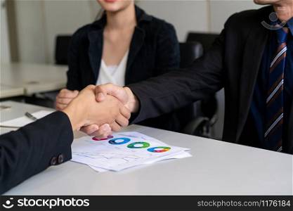 Business people agreement concept. Businessman and Asian businesswoman do handshake in the office.