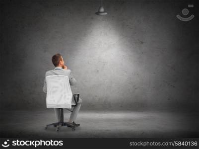 business, people and advertisement concept - businessman in suit sitting in office chair over blank white board or screen on gray wall background from back