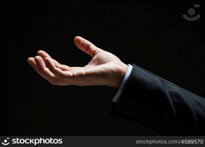 business, people and advertisement concept - close up of businessman with empty hand over black