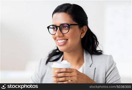 business, people and break concept - happy businesswoman drinking coffee from paper cup at office. businesswoman with coffee in paper cup at office