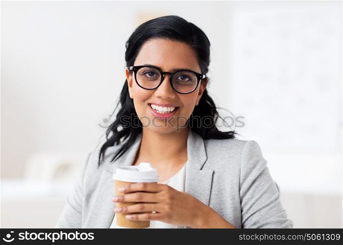 business, people and break concept - happy businesswoman drinking coffee from paper cup at office. businesswoman with coffee in paper cup at office