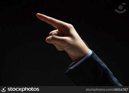 business, people and choice concept - close up of businessman hand pointing finger to something invisible over black background