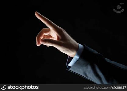 business, people and choice concept - close up of businessman hand pointing finger to something invisible over black background. close up of hand pointing finger to something