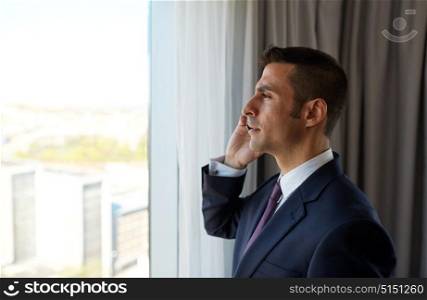 business, people and communication concept - businessman calling on smartphone at hotel room. businessman calling on smartphone at hotel room