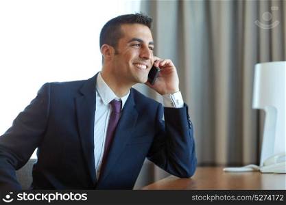 business, people and communication concept - happy smiling businessman calling on smartphone at hotel room. businessman calling on smartphone at hotel room