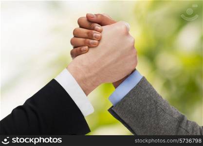 business, people and competition concept - close up of two people hands arm wrestling over green background