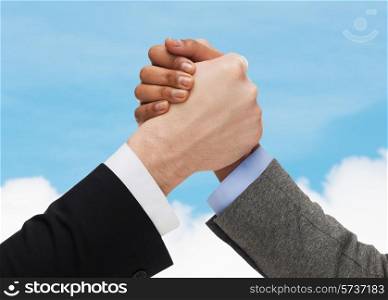 business, people and competition concept - close up of two people hands arm wrestling over blue sky and white cloud background
