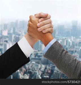 business, people and competition concept - hands of two people armwrestling over green background