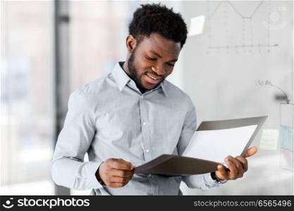 business, people and corporate concept - african american businessman with folder at office. african american businessman with folder at office