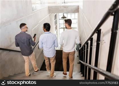 business, people and corporate concept - group of men walking down office stairs and talking. men walking down office stairs and talking