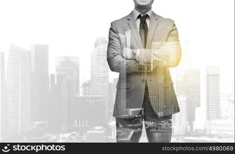 business, people and corporate concept - handsome businessman with crossed arms over over city skyscrapers background and double exposure effect. businessman with crossed arms over city buildings