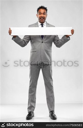 business, people and corporate concept - happy indian businessman with white banner over grey background. happy indian businessman with white banner