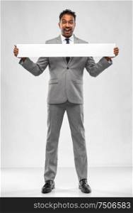 business, people and corporate concept - happy indian businessman with white banner over grey background. happy indian businessman with white banner