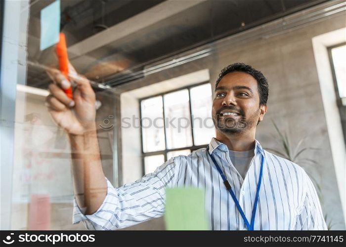 business, people and corporate concept - happy smiling businessman with glass board working at office. businessman with glass board working at office