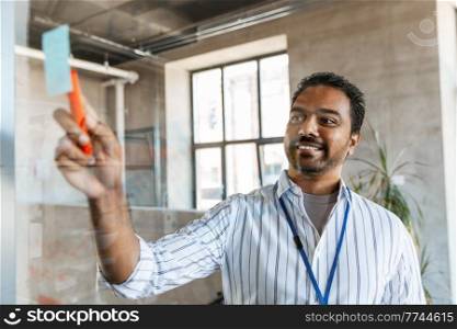 business, people and corporate concept - happy smiling businessman with glass board working at office. businessman with glass board working at office