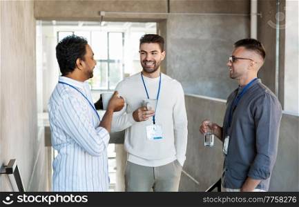 business, people and corporate concept - happy smiling businessmen with name tags drinking coffee and water at office. businessmen drinking coffee and water at office