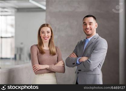 business, people and corporate concept - happy smiling businesswoman and businessman at office. smiling businesswoman and businessman at office