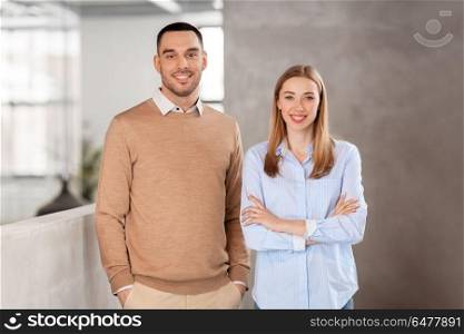 business, people and corporate concept - happy smiling businesswoman and businessman at office. smiling businesswoman and businessman at office. smiling businesswoman and businessman at office