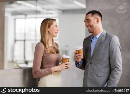 business, people and corporate concept - happy smiling businesswoman and businessman drinking coffee at office. businesswoman and businessman at coffee break