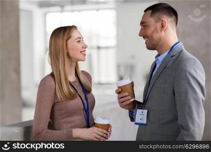 business, people and corporate concept - happy smiling businesswoman and businessman with conference badges talking at coffee break. businesswoman and businessman at coffee break. businesswoman and businessman at coffee break