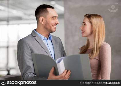 business, people and corporate concept - happy smiling businesswoman and businessman with folder at office. businesswoman and businessman with folder