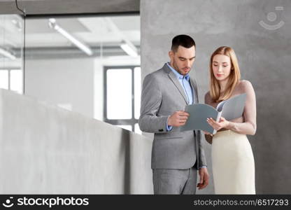 business, people and corporate concept - happy smiling businesswoman and businessman with folder at office. businesswoman and businessman with folder. businesswoman and businessman with folder