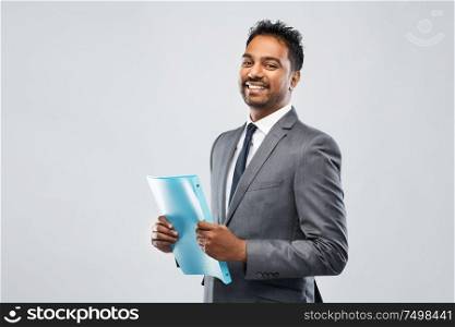 business, people and corporate concept - indian businessman with folder over grey background. indian businessman with folder over grey