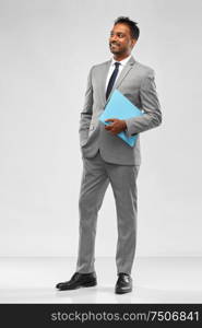 business, people and corporate concept - indian businessman with folder over grey background. indian businessman with folder over grey