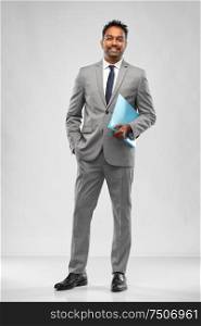 business, people and corporate concept - indian businessman with folder over grey background. indian businessman with folder over grey