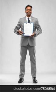 business, people and corporate concept - indian businessman with pen and papers on clipboard over grey background. indian businessman with contract on clipboard