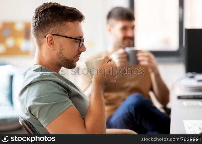 business, people and corporate concept - male startuppers drinking coffee at office. men or startuppers drinking coffee at office