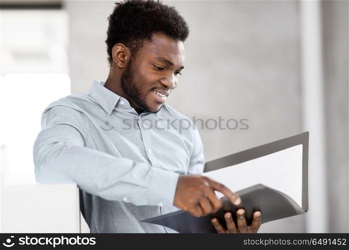 business, people and corporate concept - smiling african american businessman with folder at office. african american businessman with folder at office. african american businessman with folder at office