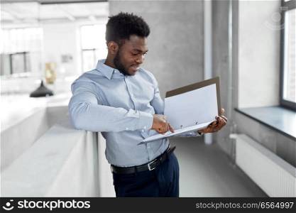 business, people and corporate concept - smiling african american businessman with folder at office. african american businessman with folder at office