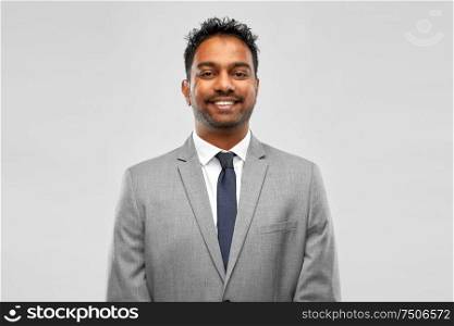 business, people and corporate concept - smiling indian businessman over grey background. smiling indian businessman over grey background
