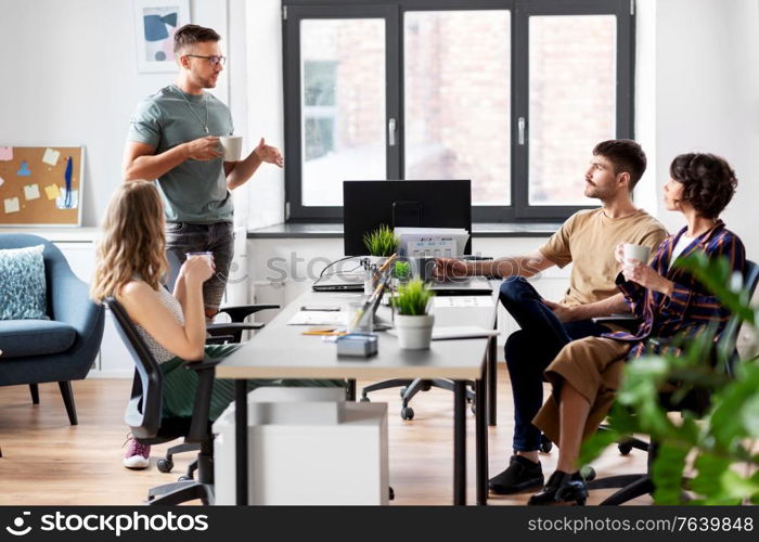 business, people and corporate concept - team of startuppers or ui designers drinking coffee at office. team of startuppers drinking coffee at office